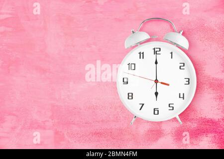 Altmodischer Wecker mit zwei Glocken und Klingelton, der 6 Uhr auf rosa Hintergrund zeigt Stockfoto
