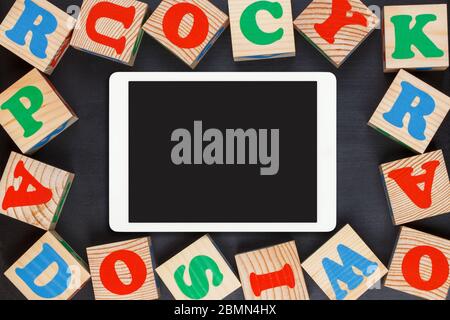 Tablet Touchpad mit bunten Alphabet Holzblöcke auf schwarzem Hintergrund. Flaches Lay Stockfoto
