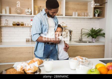 Dankbar kleines Mädchen umarmt ihren Papa mit Liebe in der Küche Stockfoto