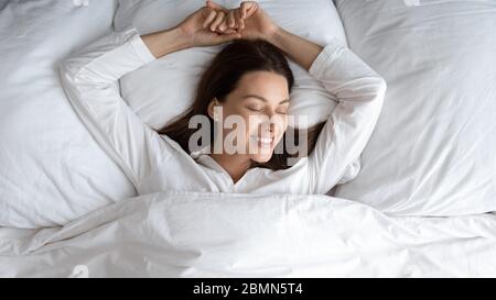 Von oben gesehen, Frau im Bett liegend, die nach dem Schlafen aufwacht Stockfoto