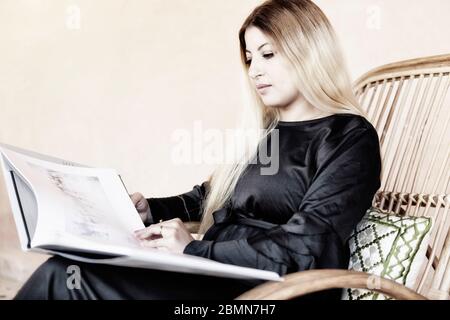 Eine schöne blonde marokkanische arabische Frau genießt eine Fotografie Kunst Couchtisch Buch. Freizeitaktivitäten während der Freizeit zu Hause. High-Key-Bild. Stockfoto