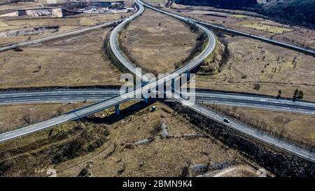 Luftaufnahme einer Autobahnkreuzung in einer ländlichen und bergigen Gegend. Wir sind tagsüber und die Straße ist nicht sehr voll. Stockfoto