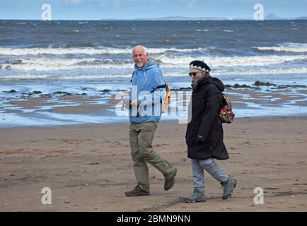 Portobello, Edinburgh, Schottland, Großbritannien. Mai 2020. Ruhige Küste mit 7 Grad und Wind von 22 km/h mit möglichen Böen von 43 km/h kein Tag für diejenigen, die nur aufdrehen, wenn es warm ist, auch keine Polizei erforderlich, da es sehr wenige mutige Seelen am Strand sitzen, So wurden die einzigen Anoraks am Strand getragen.Leute, die schnell am Sandstrand entlang laufen. Quelle: Arch White / Alamy Live News. Stockfoto