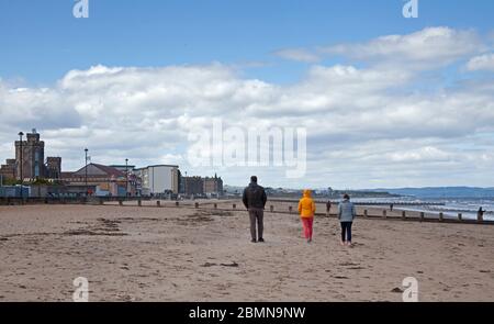 Portobello, Edinburgh, Schottland, Großbritannien. Mai 2020. Ruhige Küste mit 7 Grad und Wind von 22 km/h mit möglichen Böen von 43 km/h kein Tag für diejenigen, die nur aufdrehen, wenn es warm ist, auch keine Polizei erforderlich, da es sehr wenige mutige Seelen am Strand sitzen, So wurden die einzigen Anoraks am Strand getragen.Leute, die schnell am Sandstrand entlang laufen. Quelle: Arch White / Alamy Live News. Stockfoto