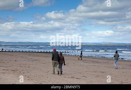 Portobello, Edinburgh, Schottland, Großbritannien. Mai 2020. Ruhige Küste mit 7 Grad und Wind von 22 km/h mit möglichen Böen von 43 km/h kein Tag für diejenigen, die nur aufdrehen, wenn es warm ist, auch keine Polizei erforderlich, da es sehr wenige mutige Seelen am Strand sitzen, So wurden die einzigen Anoraks am Strand getragen.Leute, die schnell am Sandstrand entlang laufen. Quelle: Arch White / Alamy Live News. Stockfoto