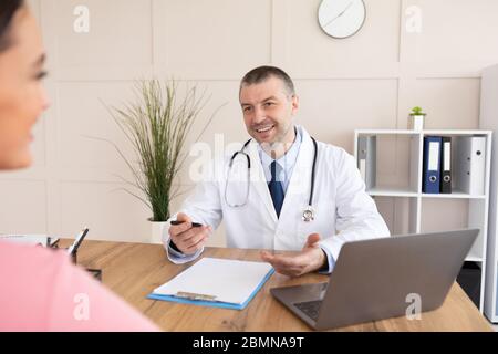 Männlicher erfahrener Arzt im Gespräch mit weiblicher Patientin Stockfoto