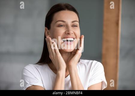 Schöne Frau berühren Gesicht genießt perfekte Haut nach feuchtigkeitsspendende Creme Stockfoto