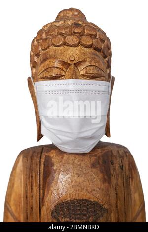 Buddha Holzstatue trägt Gesichtsmaske. Isoliert über Weiß. Covid-19-Konzept Stockfoto