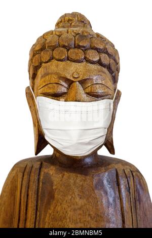 Buddha Holzstatue trägt Gesichtsmaske. Isoliert über Weiß. Covid-19-Konzept Stockfoto