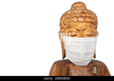 Buddha Holzstatue trägt Gesichtsmaske. Isoliert über Weiß. Covid-19-Konzept Stockfoto