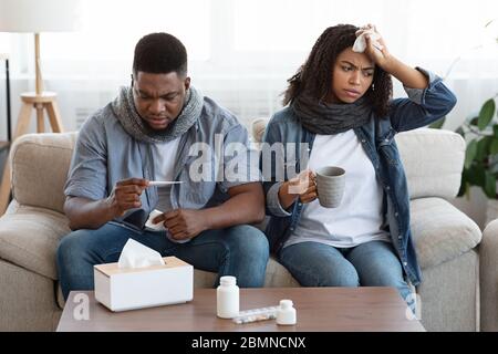 Behandlung Des Coronavirus Zu Hause. Krankes Schwarzes Paar, Das An Covid-19-Symptomen Leidet Stockfoto