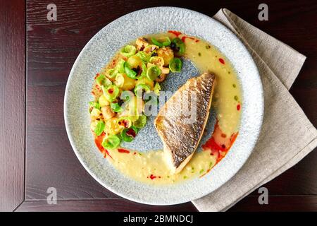 Schmackhaftes gegrilltes Seebarsch-Filet mit gedünsteten rosenkohl, gerösteten Pilzen, Kartoffeln, karamellisierten Zwiebeln und cremiger Sauce, gesundes Abendessen. Anzeigen Stockfoto