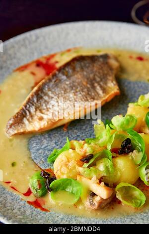 Gedämpfte rosenkohl, geröstete Pilze, Kartoffeln, karamellisierte Zwiebel und cremige Sauce mit gegrilltem Seebarsch-Filet, gesundes Abendessen. Stockfoto
