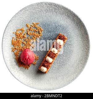 Scheibe der geschichteten Kuchen mit dunkler Schokolade Keks, Milch Mousse au Chocolat, karamellisierten Nüsse, mit Schlagsahne und garniert mit Kugel aus. Stockfoto