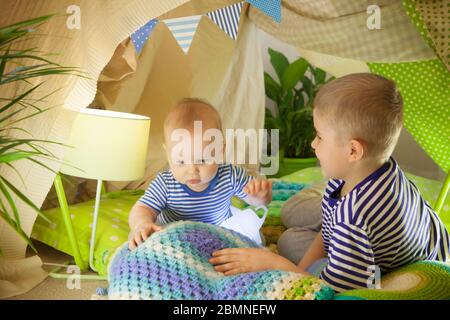 Zwei süße Brüder spielen mit einer Taschenlampe in einem Kinderzelt. 6 Jahre alter Junge und Kleinkind Stockfoto