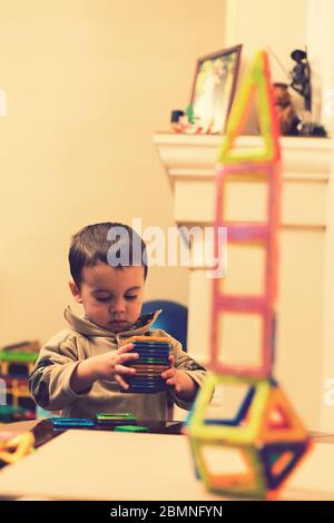 Der Junge 2 Jahre bauen einen Turm von einem hellen Konstrukteur. Kleine lächelnde Junge spielt mit magnetischen Konstruktor Spielzeug. Junge spielen intellektuelle Spielzeug Stockfoto