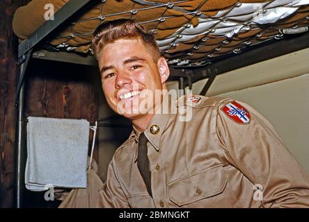 Mitte der 1950er Jahre stationiert ein US-Soldat in Deutschland – ein Mitglied der 160. Signalgruppe ist auf einem Etagenbett in der Panzer Kaserne (PK) in Böblingen abgebildet. In Uniform hat sein Haar einen Quiff, ein Stil beliebt in dieser Zeit. Ab 1955 war die 160ste Signal Group in der Nachkriegszeit unter der 7. US-Armee deutschlandweit in der Panzerkaserne (PK) in Böblingen (Böblingen) bei Stuttgart tätig. Das Hauptquartier der 7. US-Armee befand sich in der Nähe der Patch Barracks. Stockfoto