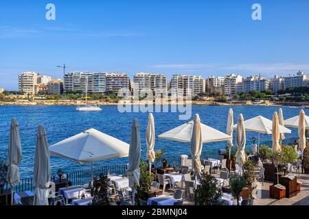 Außenrestaurants in St. Julian Stadt Terrasse am Meer in Malta mit Blick auf Sliema Stadt Skyline über die Meeresbucht. Stockfoto