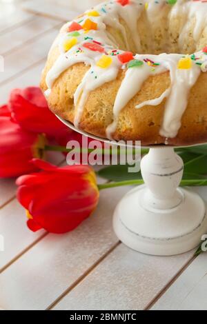 Pastellkuchen und helle Tulpen auf einem Vintage-Tisch. Ostern Familienfrühstück. Vertikales Bild Stockfoto