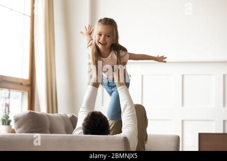 Vater hält kleine Tochter vorgibt fliegen, spielen lustiges Spiel Stockfoto