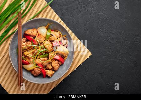 Thai Ginger Chicken oder Gai Pad King in grauer Schale auf schwarzem Schiefer Hintergrund. Gai Pad King ist Thailand Küche Gericht mit Hühnerfleisch, Ingwer Streifen, onio Stockfoto
