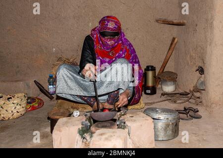 Omanische Frau in traditioneller Kleidung röstet Kaffeebohnen im Bait al Safah Museum in Al Hamra Stockfoto