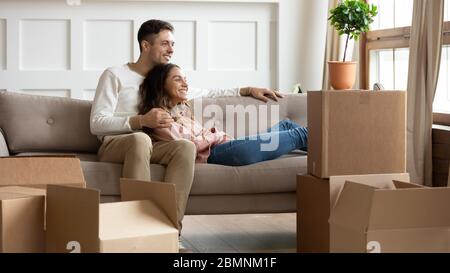 Glückliches junges Paar, das sich am Tag des Umziehenden auf der Couch entspannt Stockfoto