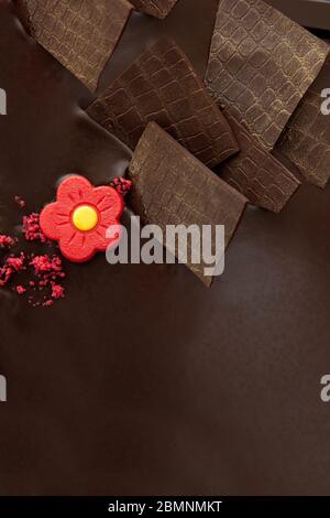 Schokoladenkuchen mit Schokoladenverzierungen und roter Marzipanrose Stockfoto