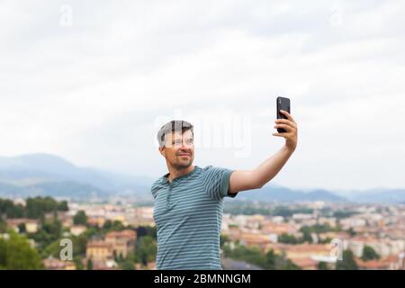 Happy Smiling man, der in einer Stadt Fotos und Selfies mit dem Smartphone macht. Reisekonzept. Reisender. Sommerurlaub. Stockfoto