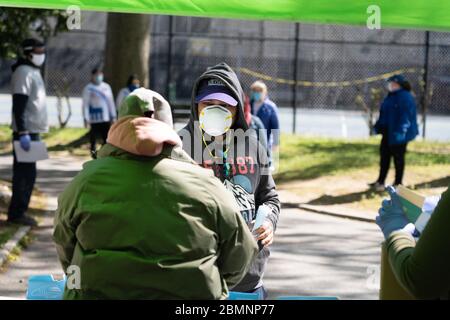 NEW YORK, NY - 10. MAI 2020: Ein Mann erhält kostenlose Gesichtsmasken aus den NYC Parks im Astoria Park inmitten der Coronavirus-Pandemie (Covid-19). Stockfoto