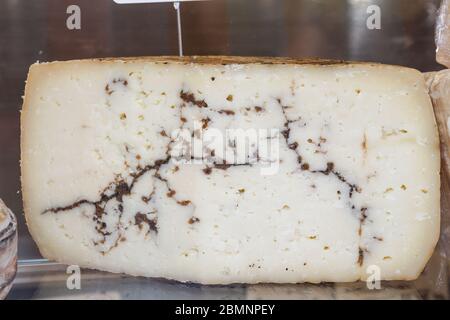 Brie Art von Käse. Camembert-Käse. Frischer Brie-Käse und eine Scheibe auf einem Holzbrett mit Nüssen, Honig und Blättern. Italienischer, französischer Käse. Stockfoto