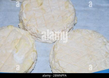 Brie Art von Käse. Camembert-Käse. Frischer Brie-Käse und eine Scheibe auf einem Holzbrett mit Nüssen, Honig und Blättern. Italienischer, französischer Käse. Stockfoto