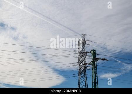 Stromturm mit seinen Kabeln. Teilweise hellblauer Himmel, große weiße Wolke. Zwei Wege in der Wolke, eine weiß, die andere blau. Svaty Jur, Slowakei. Stockfoto