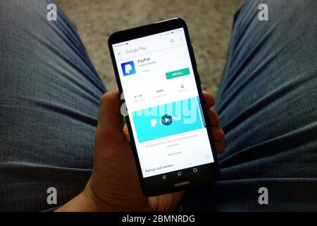 Mann hält Huawei Smartphone mit PayPal App auf Google Play Store Website angezeigt Stockfoto