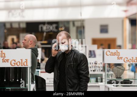 HUDDERSFIERLD, WEST YORKSHIRE, UK - MÄRZ 21: Ein Stallhalter im Kingsgate Shopping Centre telefoniert mit einer Gesichtsmaske. Stockfoto