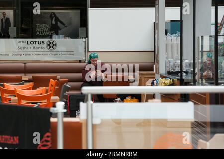 HUDDERSFIERLD, WEST YORKSHIRE, Großbritannien - MÄRZ 21: Eine Frau sitzt in einem geschlossenen Café im Kingsgate Shopping Centre in Huddersfield. Viele Restaurants und Cafés a Stockfoto