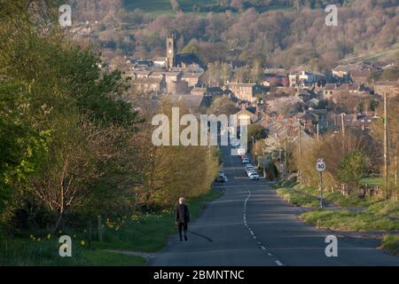 HUDDERSFIELD, WEST YORKSHIRE, UK - APRIL 11: Ein Mann geht eine einsame Straße in Honley Village in West Yorkshire hinunter. Stockfoto