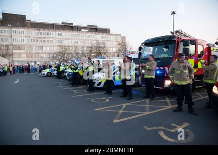 Polizeibeamte und Feuerwehrleute aus West Yorkshire stellen sich vor dem Huddersfield Royal Infirmary zusammen, um während des C Anerkennung für die Gesundheitsarbeiter zu zeigen Stockfoto