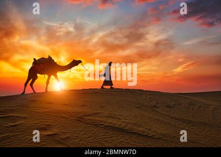 Kamelfahrer mit Kamelfiguren in den Dünen bei Sonnenuntergang. Jaisalmer, Rajasthan, Indien Stockfoto