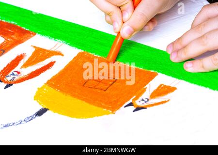 Ein Kind zieht eine glückliche Familie und ein Haus mit Buntstiften. Stockfoto