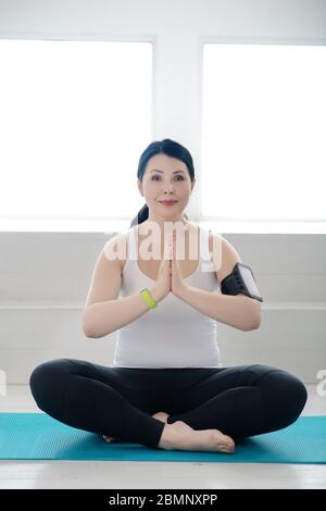 Brunette Frau sitzt auf Teppich in Lotus Pose Stockfoto