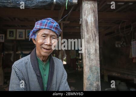 Yandabo Myanmar - Oktober 28 2013; ein älterer Mann steht und lächelt unter seinem Haus, gut gekleidet in einem abgelegenen Dorf. Stockfoto