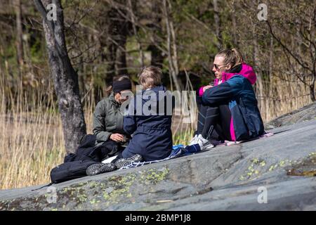Drei Frauen machen eine Pause auf einem Felsen am Uutela Naturwanderweg im Vuosaari Bezirk in Helsinki, Finnland Stockfoto