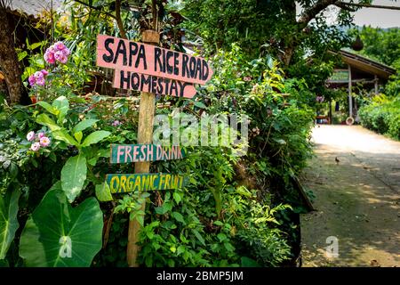 SA pa, Vietnam - 24. April 2018: Handgefertigte Schilder zu einer Gastfamilie, mit bunten Schrift und blühenden Pflanzen, an einem teilweise bewölkten Tag aufgenommen Stockfoto