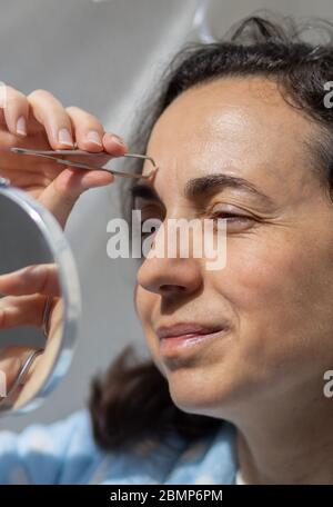Hübsche junge hispanische Frau reinigt ihre Augenbrauen Stockfoto