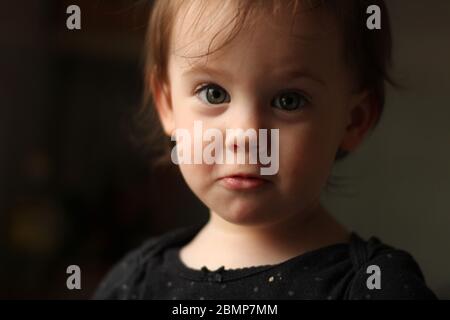 Nahaufnahme Porträt eines kleinen niedlichen weißen Babys mit einem schmutzigen Gesicht in weichem Licht und verschwommenem Hintergrund