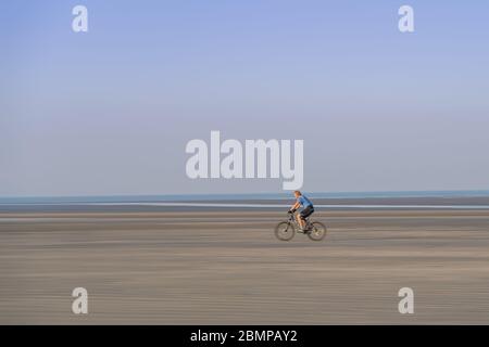 Radfahrer radeln mit Geschwindigkeit auf dem flachen Sand auf West Wittering Beach Stockfoto