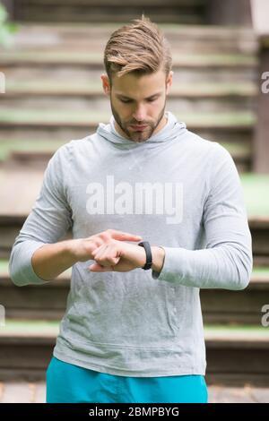 Überwachung der Herzfrequenz vom Handgelenk aus. Sportliche Herren Karuhr. Gutaussehende Sportler verwenden intelligente Uhr. Fitness-Tracking. Verfolgen Sie Distanz und Schritte mit der Uhr. Workout Tracker und Uhr. Sporttechnologie. Stockfoto