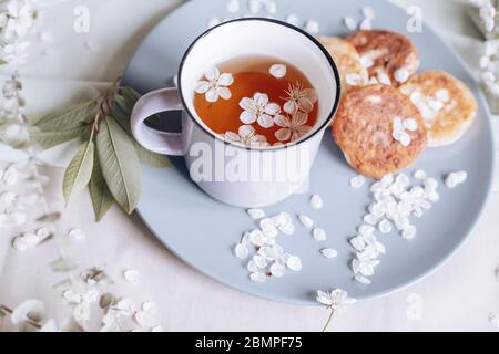 Frühstück am Morgen, getoastete schöne Käsekuchen auf einem Teller auf der Tischdecke neben einem Frühlingsstrauß aus weißen Blumen Stockfoto