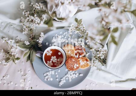 Frühstück am Morgen, getoastete schöne Käsekuchen auf einem Teller auf der Tischdecke neben einem Frühlingsstrauß aus weißen Blumen Stockfoto